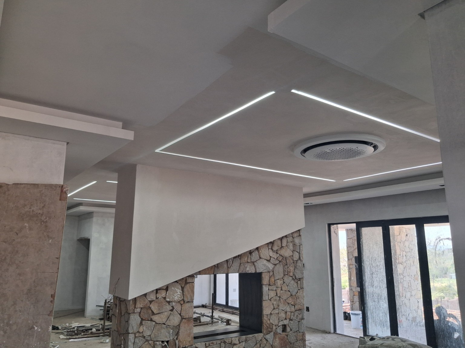 Actual interior construction photograph with a stone fireplace and sculpted illuminated ceiling